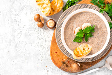 Mushroom cream soup. Champignon soup puree, toast and parsley on a gray concrete background top view. Free space for text. Tasty winter food, vegetarian food. Copy space.
