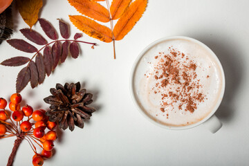 Obraz na płótnie Canvas Close-up of a cup of coffee with cinnamon. Supernova view of an autumn composition, colorful leaves, sea buckthorn on a white background