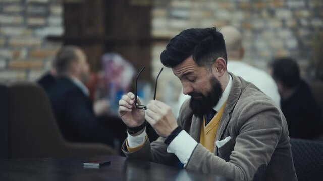 Bearded businessman in glasses bears losses from fatigue rubs his eyes