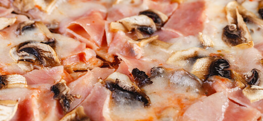 Pizza with ham and mushrooms on wooden board on dark background. Close-up