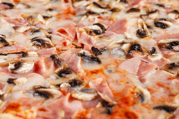 Pizza with ham and mushrooms on wooden board on dark background. Close-up