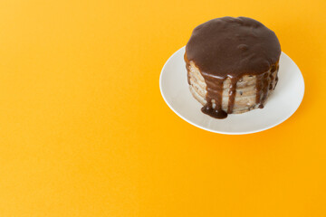 Chocolate cake with streams on a plate. Halloween celebration concept, trick or treat. Handmade cooking, brownies with flows down. Orange background, copy space. Selective focus, blur.