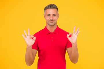 Satisfactory result. Happy man show double OK signs yellow background. Satisfied guy smile with satisfaction. Agreement and confirmation. Satisfactory solution