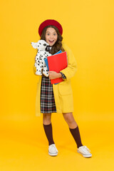 education concept. childhood happiness. school and fashion. child in pupil uniform. kid in french beret on yellow background. stylish teen college student. little girl with toy dog and notebooks