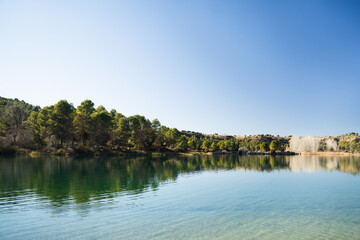 Beautiful and calm lagoon with trees in the background in the natural park of 'Lagunas de Ruidera' in Ossa de Montiel, Albacete, Spain