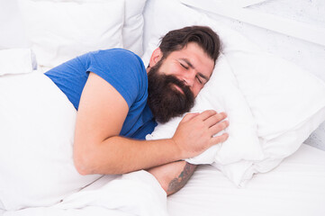 pleased caucasian brutal man with mustache smiling in bed at bright room, healthy lifestyle