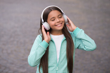 cheerful girl wear earphones with music song outdoor enjoying melody, school online education