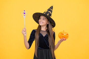 happy witch kid with magic wand and pumpkin jack o lantern wear costume of wizard on halloween...