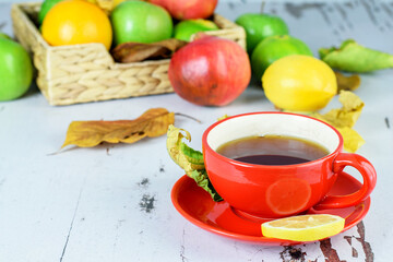 Cup of tea with lemon, assortment of tropical citrus on the rustic wooden table. Autumn season, home relaxing concept.