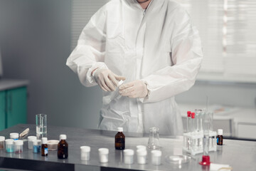 Fototapeta premium A close up picture of the scientists hands holding a chemical sample and a table with various laboratory glassware.