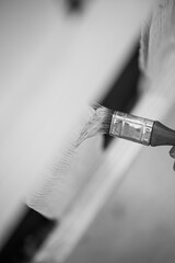 Monochrome image of using a paintbrush to varnish a wooden fence