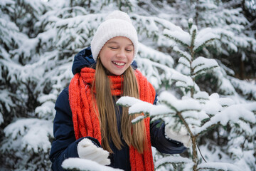 A beautiful schoolgirl spends her holidays in a country house and walks through a winter forest with firs, pines and snow