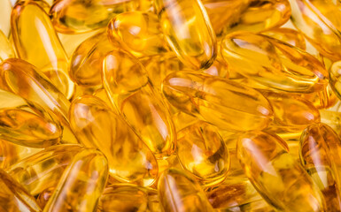 Close up of fish oil orange yellow softgels capsules fish oil omega 3 or omega 6, omega 9, vitamin A, vitamin D, vitamin E background. Healthy vitamins product concept