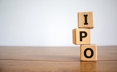 Concept word 'IPO' - 'initial public offering' on wooden cubes on a beautiful woodet table, white background. Business concept. Copy space.