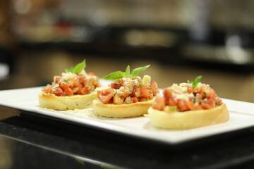 Garlic bread (traditional bruschetta) on the white plate with tomatos, cheese, olive oil and others ingredients