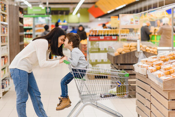 woman and child boy during family shopping with trolley at supermarket