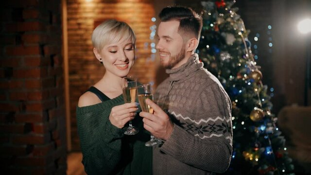 A young couple are happy kissing each other at christmas, holding glasses of champagne.
