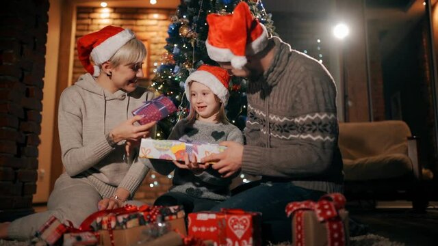 Happy parents are giving their girl christmas presents.