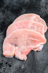 Raw Turkey steaks. Organic poultry meat. Black background. Top view