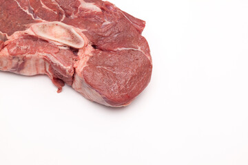 Fresh large piece of meat. Juicy beef with a bone for broth on a light background. Close-up, copy space