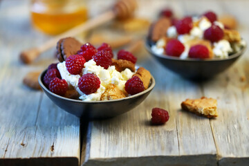 Mascarpone dessert with raspberries and biscuits in bowls.
