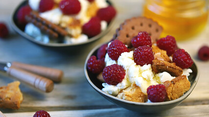 Mascarpone dessert with raspberries and biscuits in bowls.