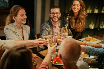Group of friends sitting in restaurant and making a toast with wine for promotion.