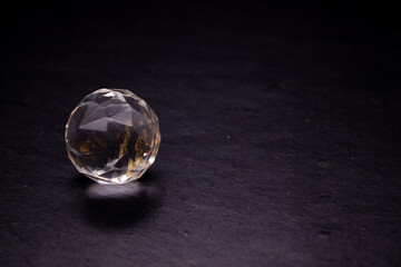 Faceted sphere, sparkling crystal on dark, black background. Large glass with light refraction,...