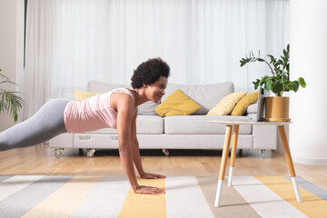Woman exercising as shown online on digital tablet
