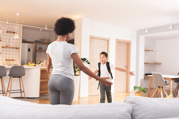 Mother about to embrace excited son coming from school to home