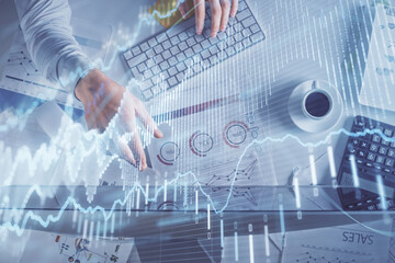 Multi exposure of man's hands typing over computer keyboard and forex graph hologram drawing. Top view. Financial markets concept.