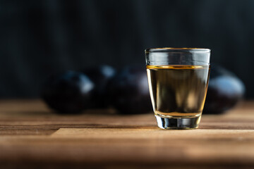 Close up on homemade strong alcohol drink from plum brandy in shot glass rakia brandy called slivovitza traditional drink made in serbia croatia bulgaria or bosnia with selective focus dark background