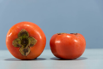 Fresh persimmon fruits on blue background