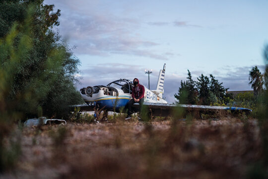 Chico con capucha y mascarilla negra en avion abandonado destrozado