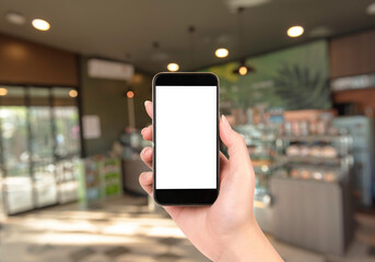 Hand holding smartphone  with white blank screen and blurred coffee shop background.