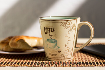 Picture of a cup of coffee, a plate with croissants and a mobile phone