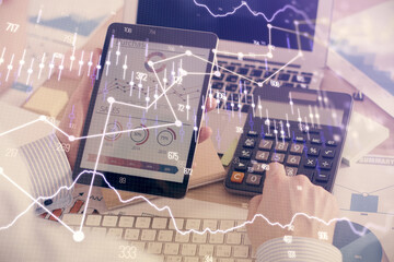 Double exposure of man's hands holding and using a digital device and forex graph drawing. Financial market concept.