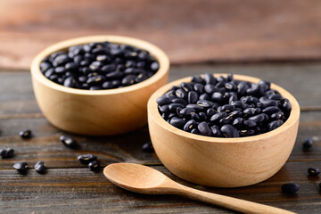 Black kidney beans in a bowl and spoon on wooden background