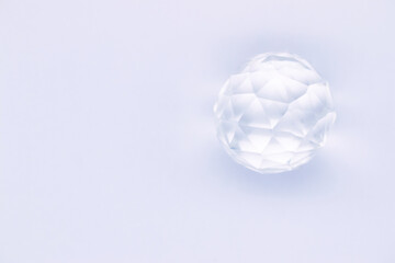 Faceted sphere, sparkling crystal on white background. Glass object with light refraction, empty space for inscriptions