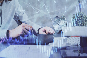 Double exposure of man's hands holding and using a phone and financial graph drawing. Analysis concept.