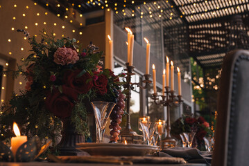 Christmas table with candles, flowers and glass cups.
