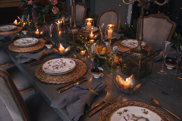 Christmas table with candles, flowers and glass cups.
