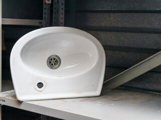 Белая раковина для ванной..
A white bathroom sink sits on a shelf on the left in a workbench with room for text on the right, a close-up side view.