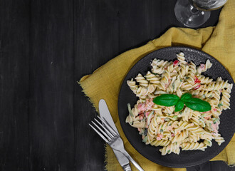 pasta with vegetables.
Fusilli pasta with white wine on a black table with place for text on the left, top view.