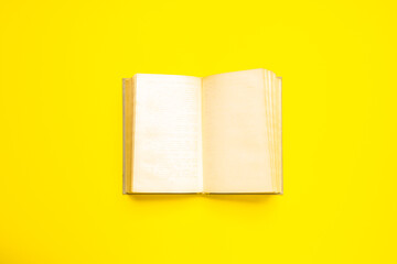 blank open vintage book on a yellow desk. studio shot. start new life concept. education backdrop
