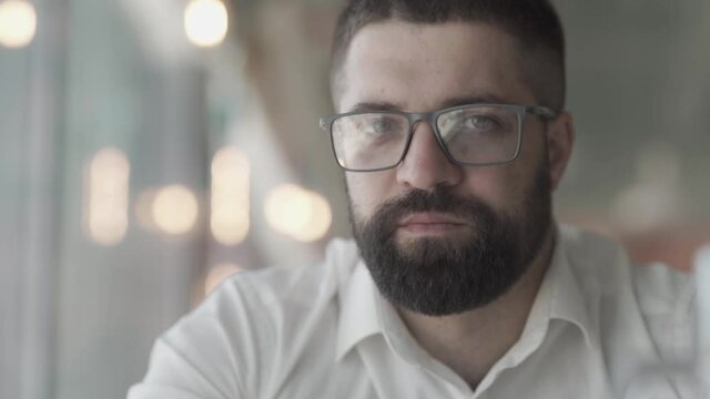 Closeup of a young bearded man with glasses. Portrait of a guy with glasses looking at the camera. LOG gamma