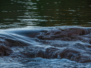 Close of shot of river water rippling and flowing through rocks