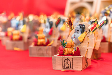 Masu cup used as an auspicious rake ornated with Japanese folklore lucky charms like Otafuku goddess of mirth, Daruma doll, rice barrel, manekineko cat or hand fan.