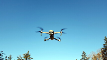 The quadcopter is flying in the blue sky. Uav. Modern technology .