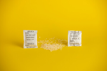 Desiccant or silica gel indifferent packaging and spread on yellow background.